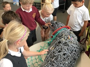 Photos showing children handing a life size ghost gear seal highlighting the need for future solutions